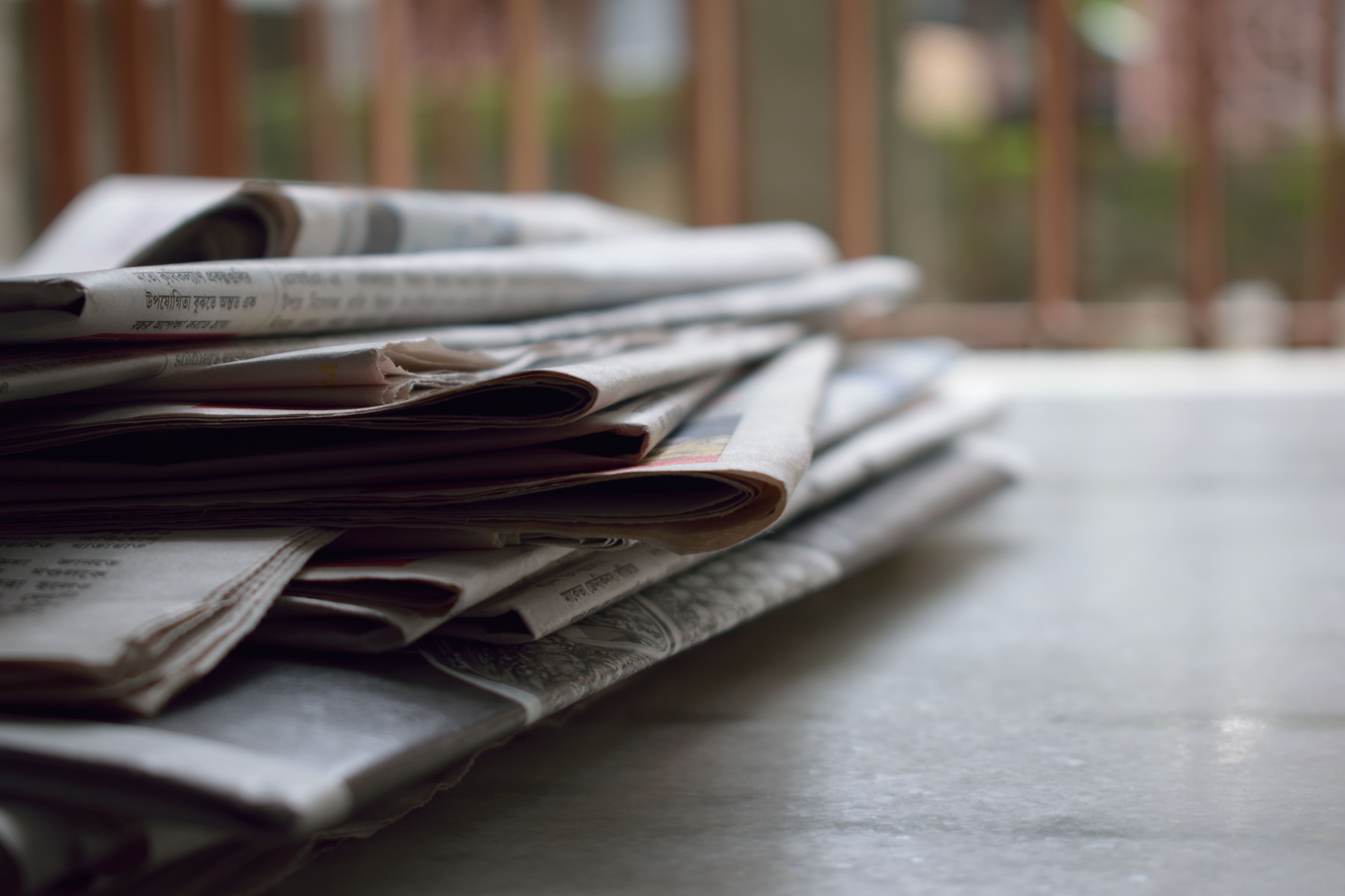 A stack of printed newspapers representing source-based reporting.