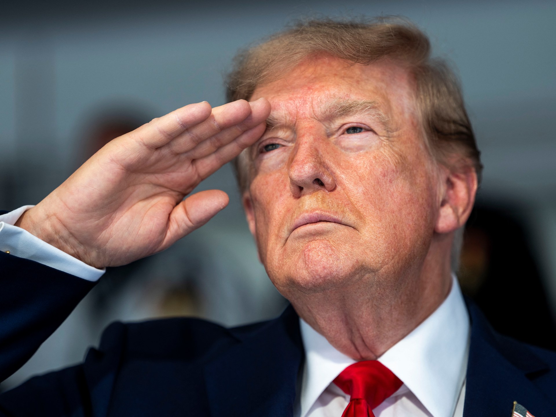 US President Donald Trump salutes during the national anthem at the start of the Freedom 250 Grand Prix Race in Washington on August 23, 2026 [AFP]