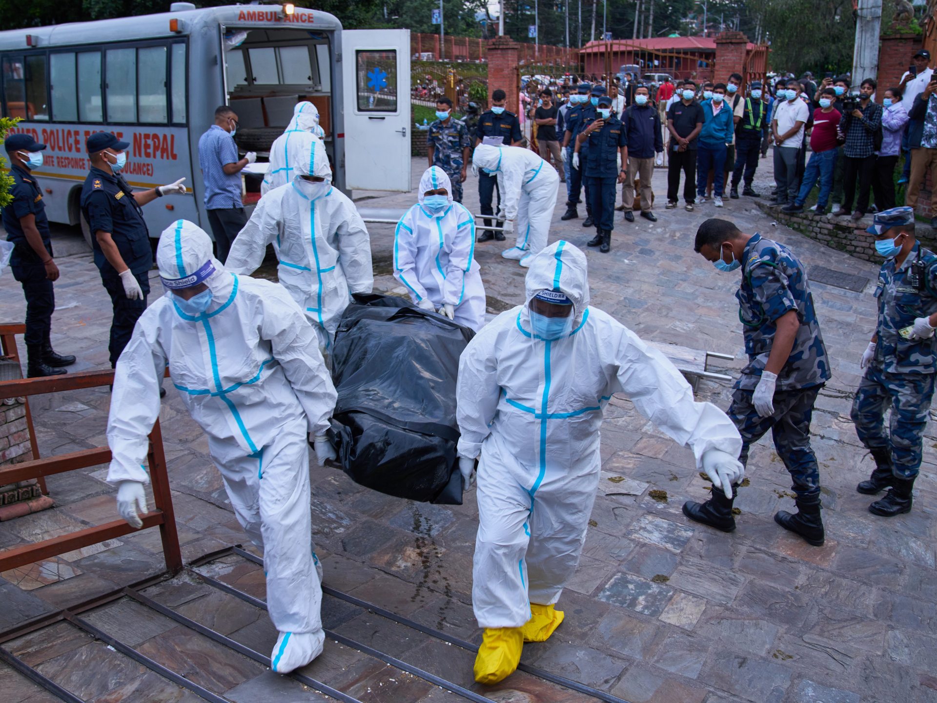 Police personnel in protective suits carry the body of an unidentified victim of the flash floods for storage at a crematorium in Kathmandu, Nepal [Dar Yasin/AP]